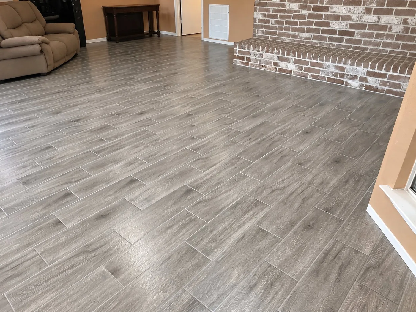 Gray wood-look tile installed in living room around brick fireplace